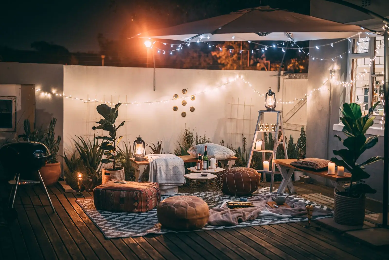 Backyard lounge with string lights and floor cushions at night