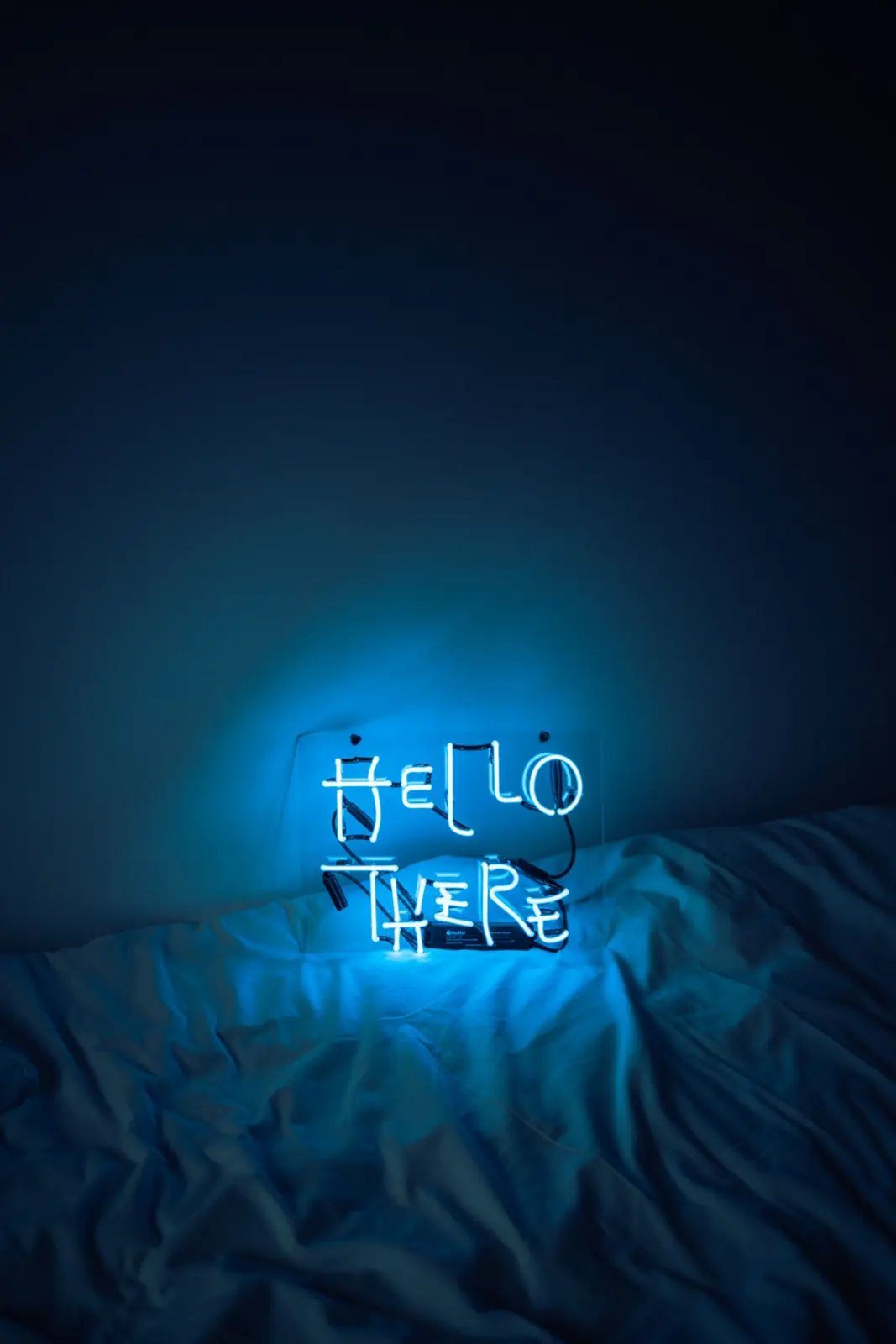 Blue neon-style sign glowing on a bed