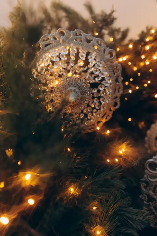 Close-up of a Christmas tree glowing with warm fairy lights and an ornament