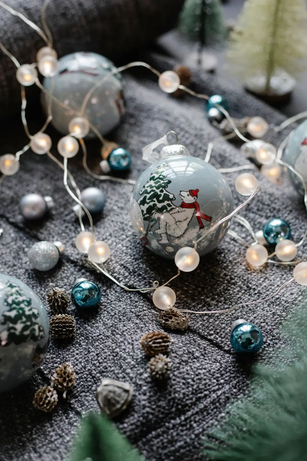 Holiday ornaments and fairy lights resting on a knit blanket