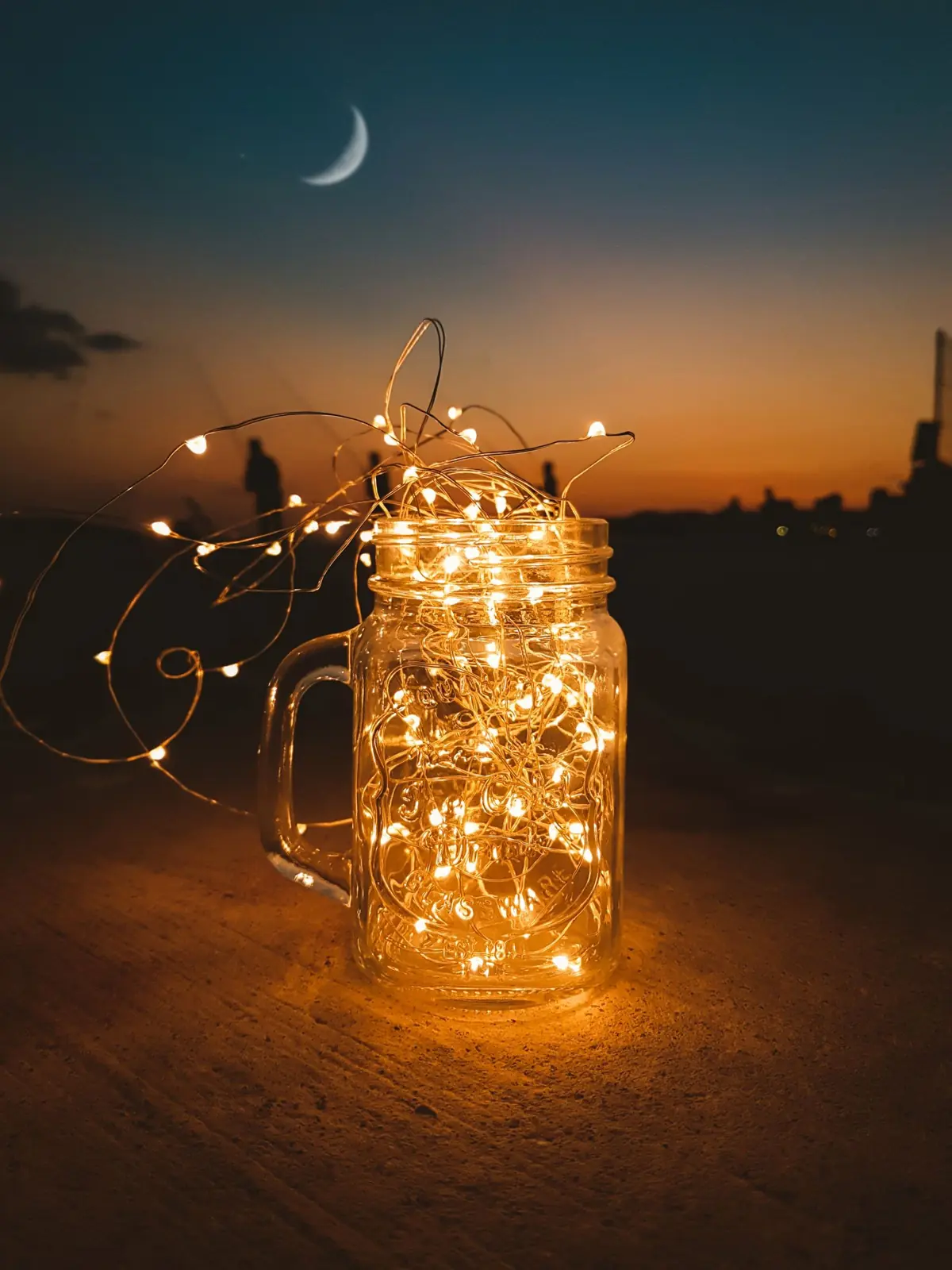 Glass jar filled with glowing fairy lights at twilight