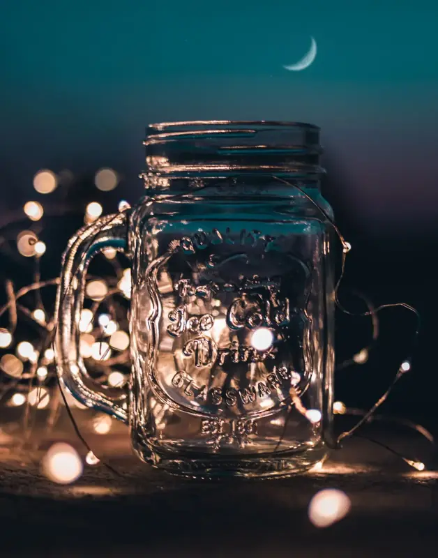 Mason jar filled with glowing fairy lights at night