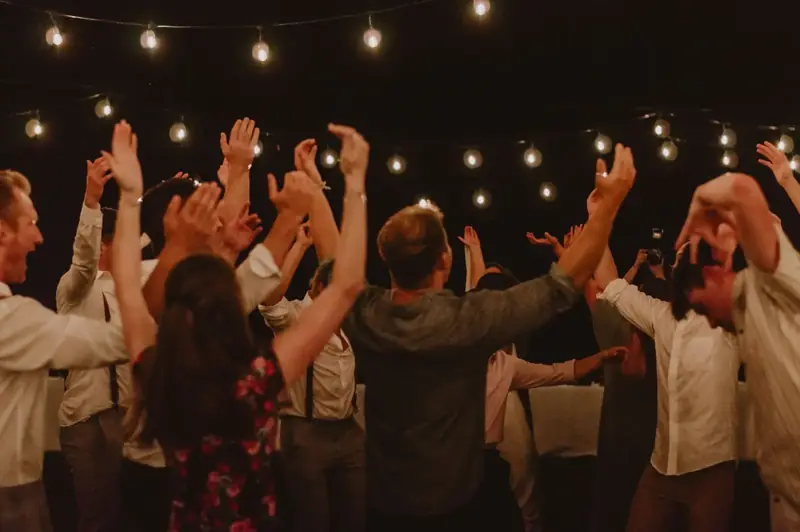 People dancing outdoors at night under strands of warm string lights