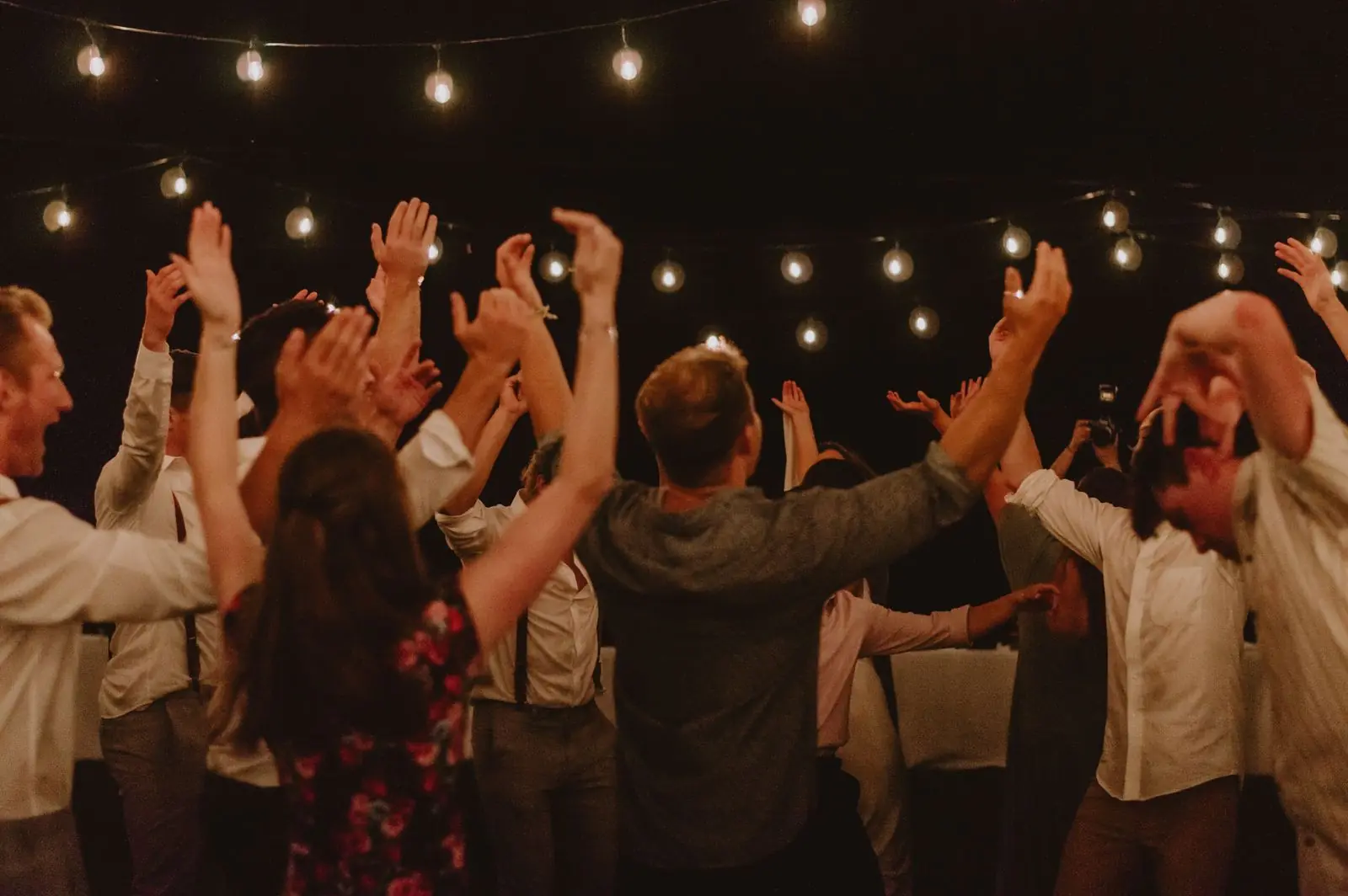 People dancing under string lights at night