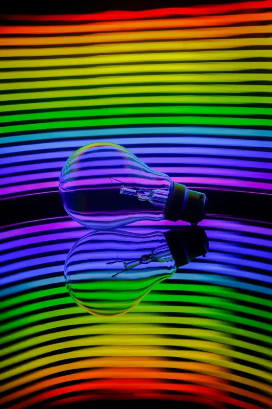 Light bulb against a rainbow-striped background