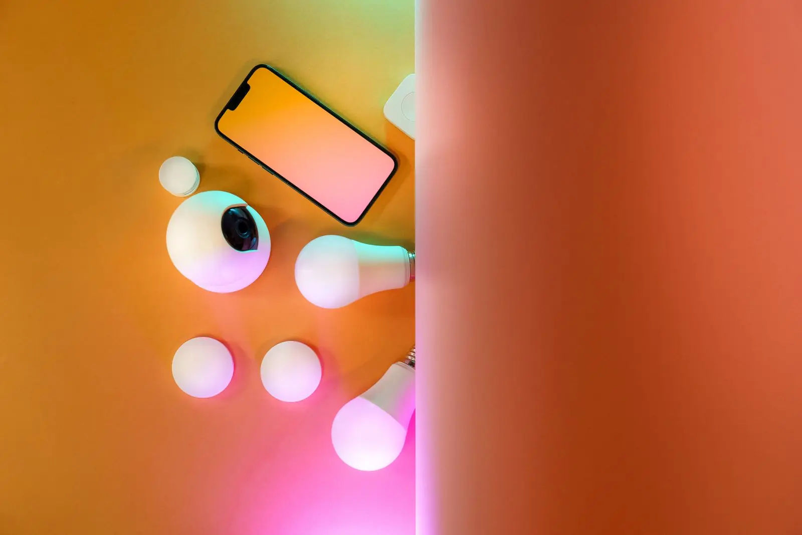 Smart bulbs next to a smartphone on an orange background